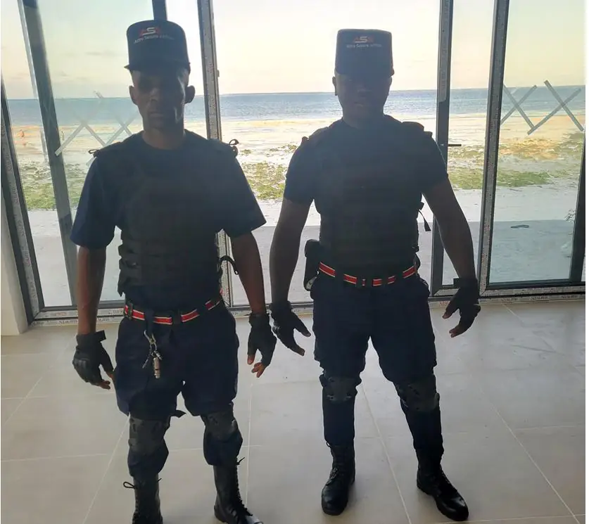 Two ASA close protection officers in tactical vests at a coastal property